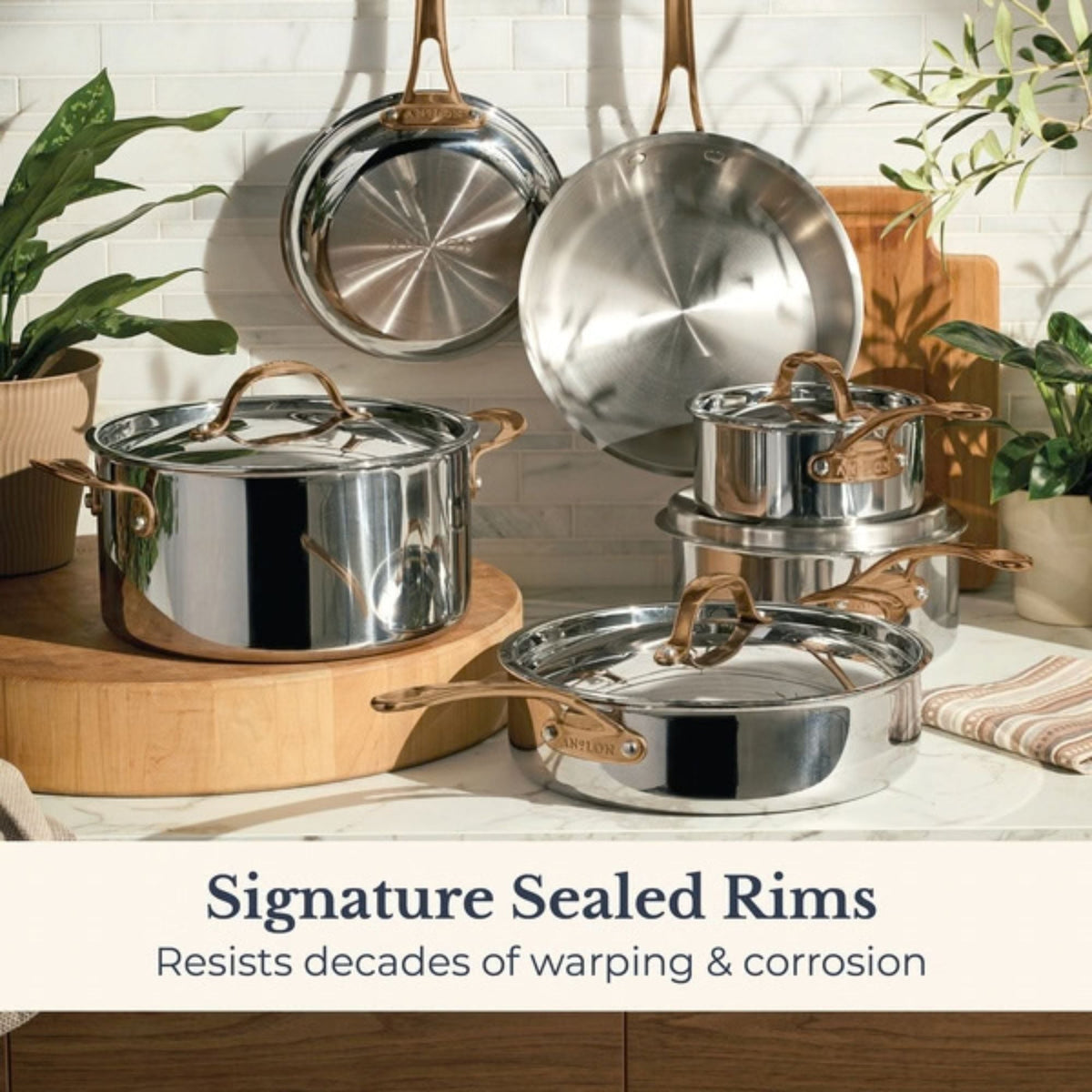 Anolon EverLast stainless steel cookware with bronze handles in a bright kitchen, highlighting signature sealed rims that resist warping